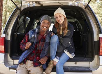 Portrait of mixed race couple sitting in open back of a car