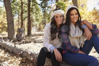 Portrait of lesbian couple sitting in a forest, to camera