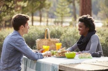 Caucasian man and Black woman talking at a picnic table