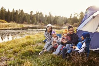 Asian family on a camping trip relax outside their tent