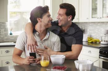 Male gay couple in their 20s embracing in their kitchen