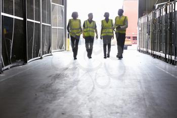 Four colleagues in reflective vests walking into a warehouse