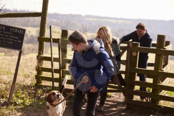Boy looks down at pet dog during family walk in countryside