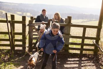 Boy leads his family and dog through a gate in countryside