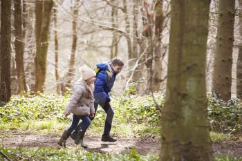 Side view of brother and sister running in a wood