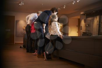 Rear View Of Pupils On School Trip To Museum Looking At Map