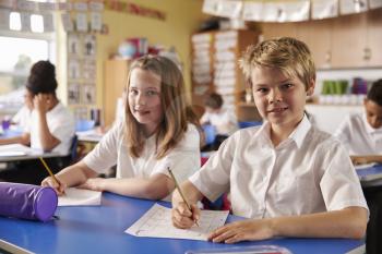 Two kids in a lesson at a primary school look to camera
