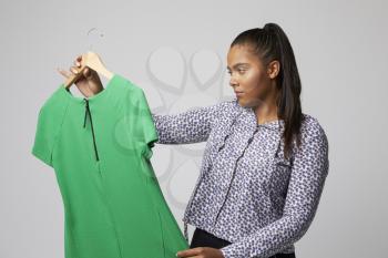 Studio Portrait Of Female Fashion Buyer Looking At Dress