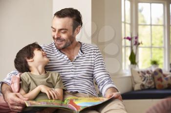 Father And Son Reading Story At Home Together