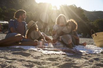 Two couples having a picnic on the beach, lens flare, Ibiza