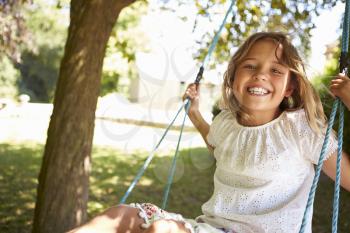 Portrait Of Young Girl Playing On Tree Swing