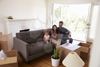 Family Take A Break On Sofa Using Laptop On Moving Day