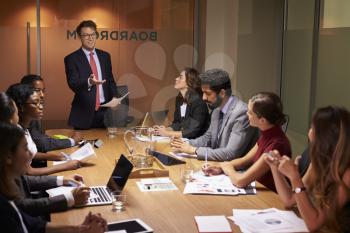 Businessman stands gesturing to colleagues at a meeting