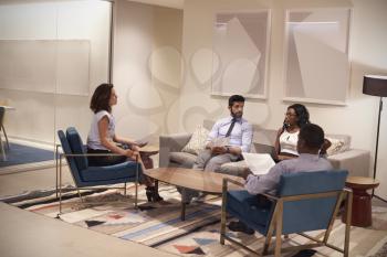 Four people meeting in lounge area of a corporate business