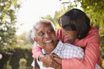 Senior black couple piggyback, looking at each other