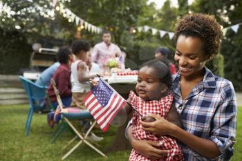 Black mother and baby holding flag at 4th July garden party