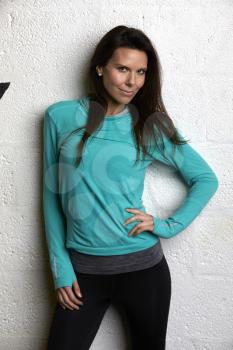 Woman Wearing Fitness Clothing Standing Against Wall Of Gym
