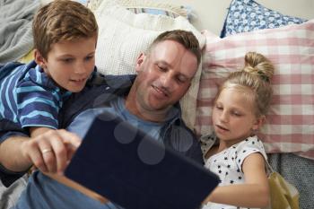 Father And Children Lying On Floor Using Digital Tablet