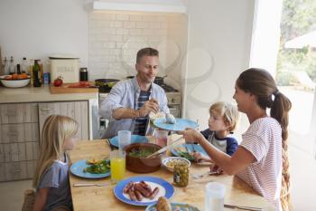 Family sitting around kitchen table serving lunch