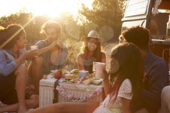 Friends talking at a picnic beside their camper van