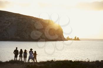 Rear View Of Friends Standing On Cliff Watching Sunset