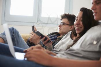 Teenage friends relax watching laptop and smartphone at home