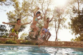 Family On Vacation Jumping Into Outdoor Pool