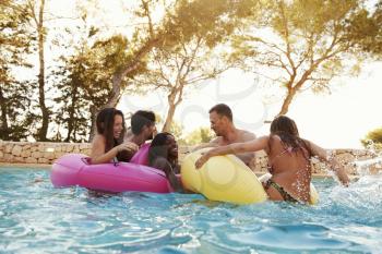 Group Of Friends On Inflatables In Outdoor Pool