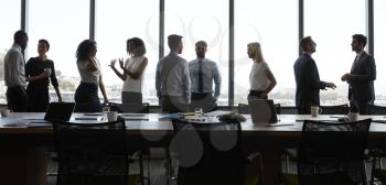 Businesspeople Stand And Chat Before Meeting In Boardroom