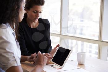 Two Businesswomen Using Digital Tablet In Office Meeting