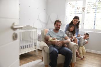Portrait Of Family With Children And Newborn Son In Nursery