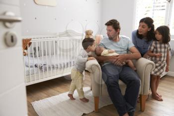Family With Children And Newborn Son In Nursery