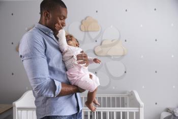 Father Holding Baby Daughter In Nursery