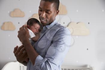 Father Holding Newborn Baby Son In Nursery