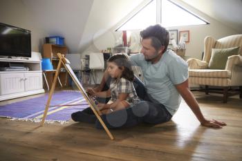 Father And Daughter Drawing On Chalkboard In Playroom