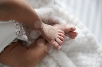 Close Up Of Feet Of Newborn Baby In Nursery Cot