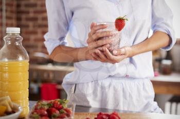 Woman holding strawberry smoothie, mid section