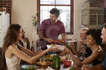 Host and friends pass food round the table at a dinner party