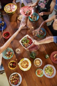 Overhead shot of friends passing food across a dinner table