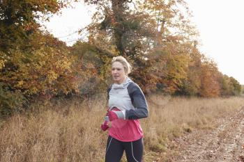 Mature Woman Running Around Autumn Field