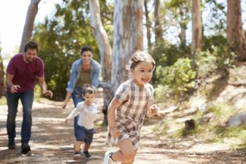 Family Running Along Path Through Forest Together