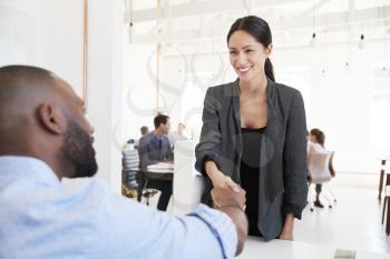 Woman greeting a black businessman at an office meeting