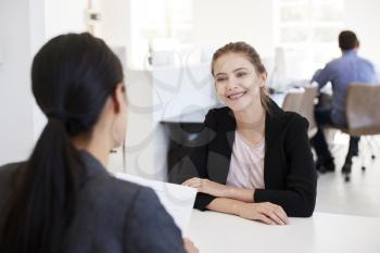 Two women sitting at an interview in an open plan office