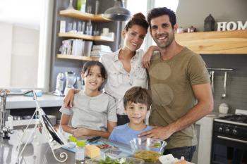 Portrait Of Family In Kitchen Following Recipe On Digital Tablet