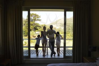 Rear View Of Family On Balcony Looking Out On New Day