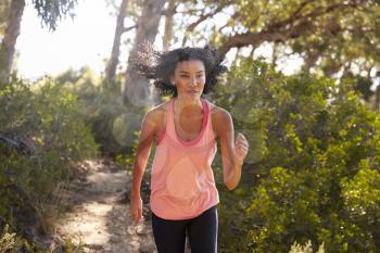 Young black woman jogging in a forest, close up