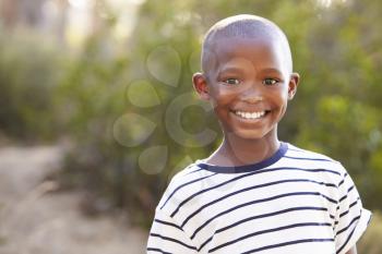 Smiling young black boy looking to camera outdoors