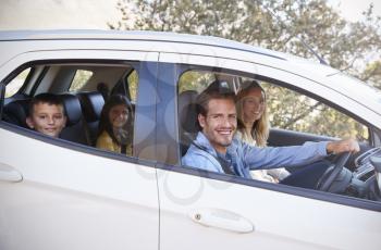 Happy young family driving in their car looking to camera