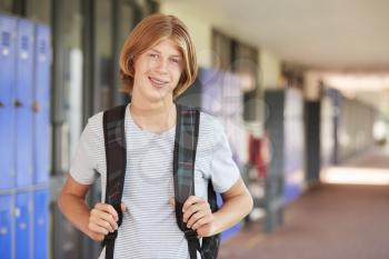 Happy white teenage boy smiling in high school corridor
