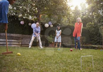 Group Of Mature Friends Playing Croquet In Backyard Together